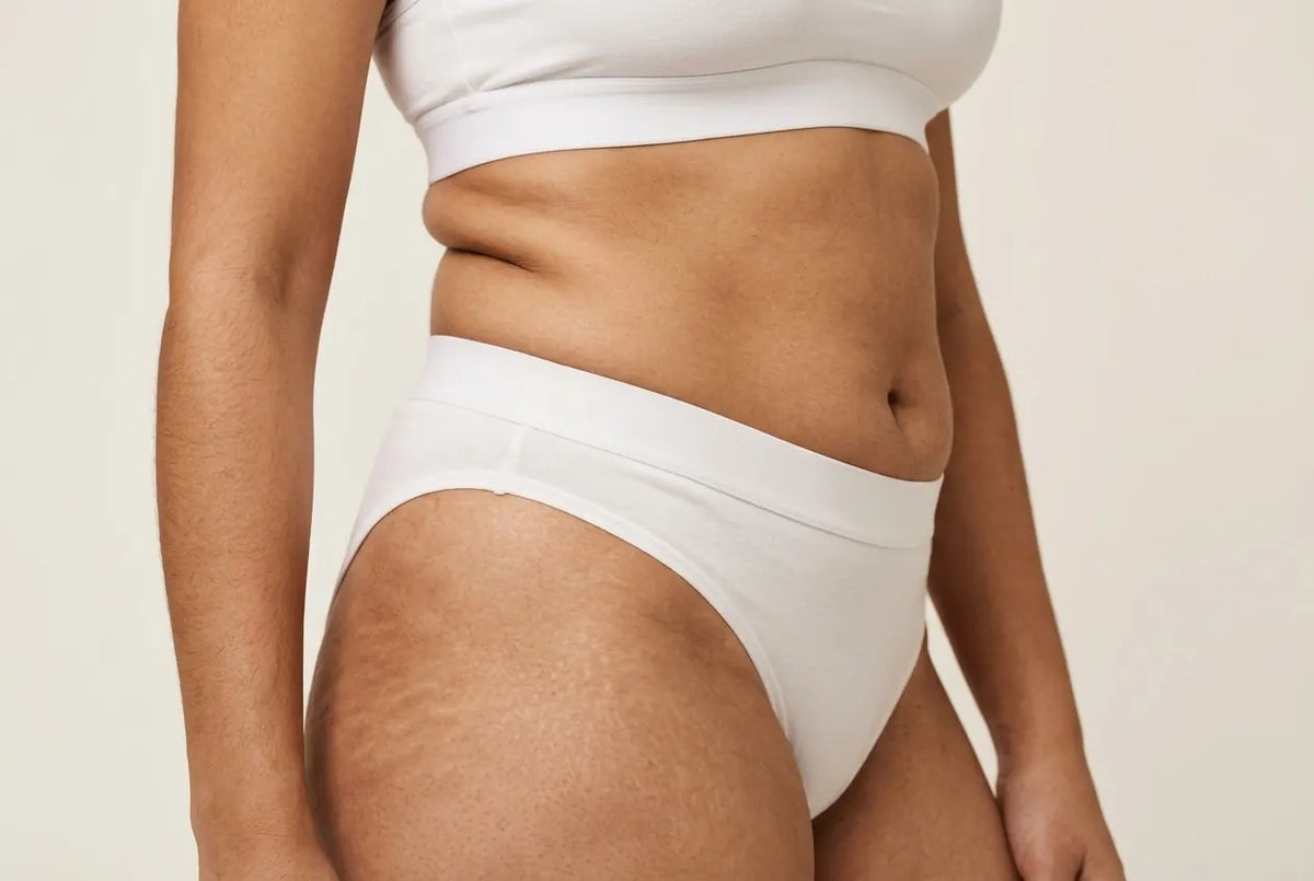 Bas-ventre légèrement arrondi chez une femme mince, en sous-vêtements blancs