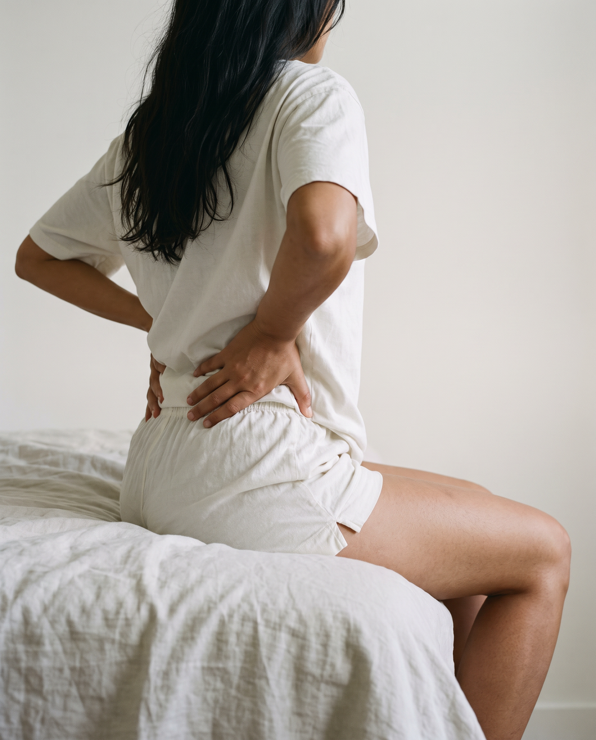 Femme assise au bord du lit avec sensation de jambes lourdes et de gonflement